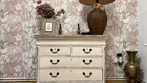 A dresser with multiple drawers and a lamp on top.