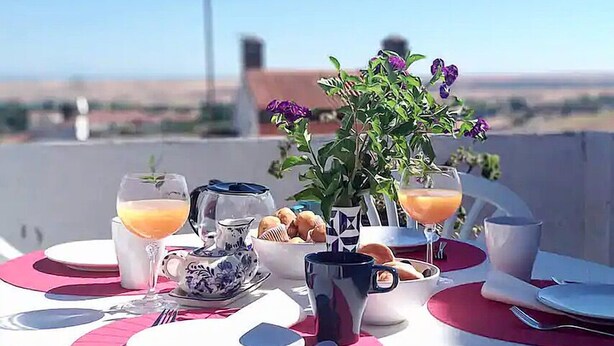 A breakfast setup on a terrace with a clear view of the landscape.
