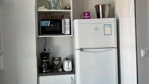 A compact kitchenette with a microwave, toaster, coffee maker, and a refrigerator.