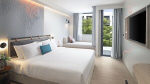 A modern hotel room with a large bed, a sofa, a TV, and a balcony with curtains. - JonoX Phuket Karon Hotel (Karon)