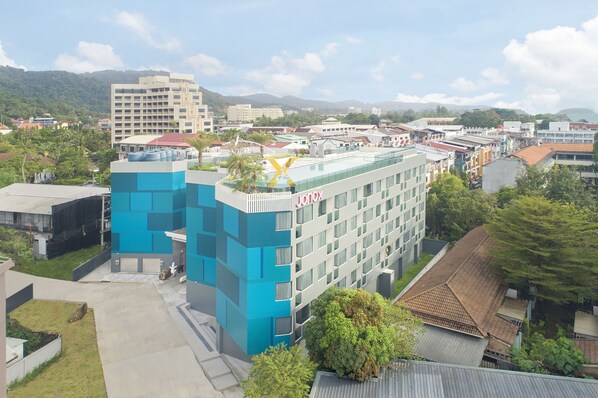 Un hôtel au design moderne, caractérisé par une palette de couleurs dominante en bleu et blanc, et doté d’un espace sur le toit avec une structure jaune.