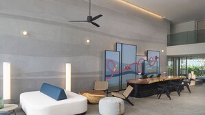 A modern lobby with a reception desk, seating area, and artwork on the walls. - JonoX Phuket Karon Hotel (Karon)