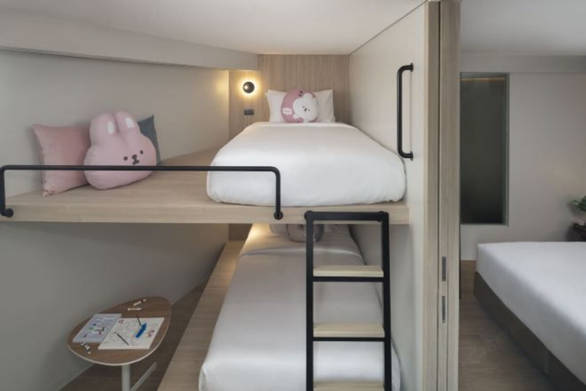 A bunk bed room with a desk, pillows, and a ladder.