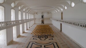 A long corridor with ornate white railings, a patterned floor, and a series of circular windows. - Montebelo Mosteiro de Alcobaça Historic Hotel (Alcobaça)
