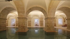 An indoor swimming pool with stone arches and a central seating area. - Montebelo Mosteiro de Alcobaça Historic Hotel (Alcobaça)