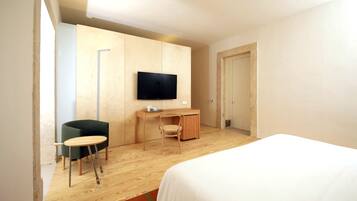 Una habitación de hotel moderna con una cama, un escritorio, una silla, un televisor y un armario.