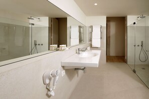 A modern bathroom with a large mirror, two sinks, a glass shower enclosure, and a hairdryer on the wall. - Montebelo Mosteiro de Alcobaça Historic Hotel (Alcobaça)