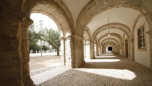 A corridor with stone arches and a cobblestone floor. - Montebelo Mosteiro de Alcobaça Historic Hotel (Alcobaça)