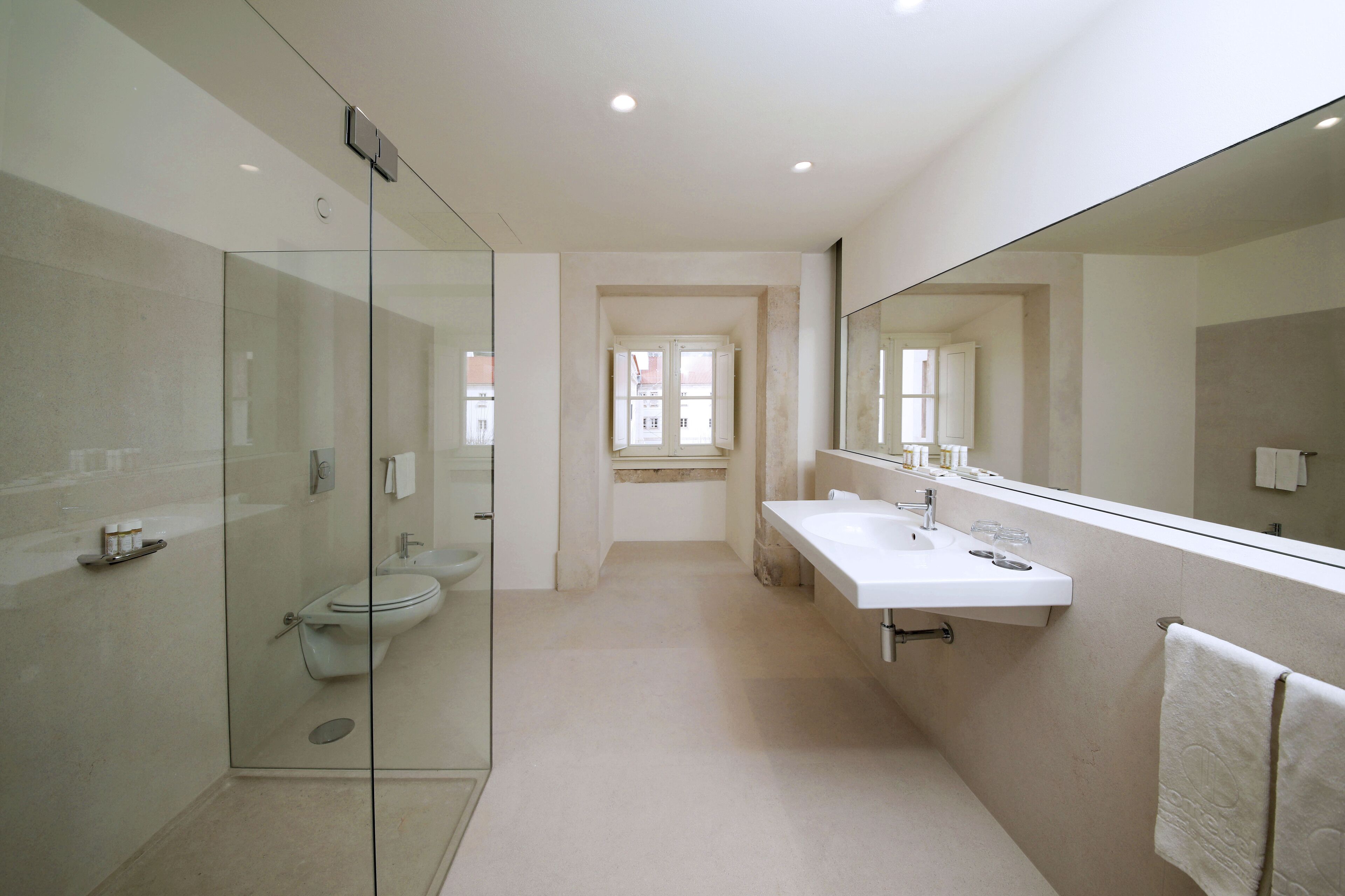A modern bathroom with a glass shower enclosure, a toilet, and a sink with a mirror.