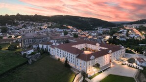 A large, historic building with multiple wings, surrounded by a town. - Montebelo Mosteiro de Alcobaça Historic Hotel (Alcobaça)