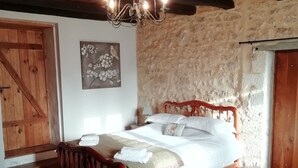 Une chambre confortable avec un lit en bois, un mur en pierre et un plafond en bois.