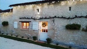 Un bâtiment en pierre avec une porte blanche, de petites fenêtres et une décoration en forme de guirlande.