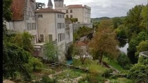 Un château doté d’un jardin et bordé par une rivière.