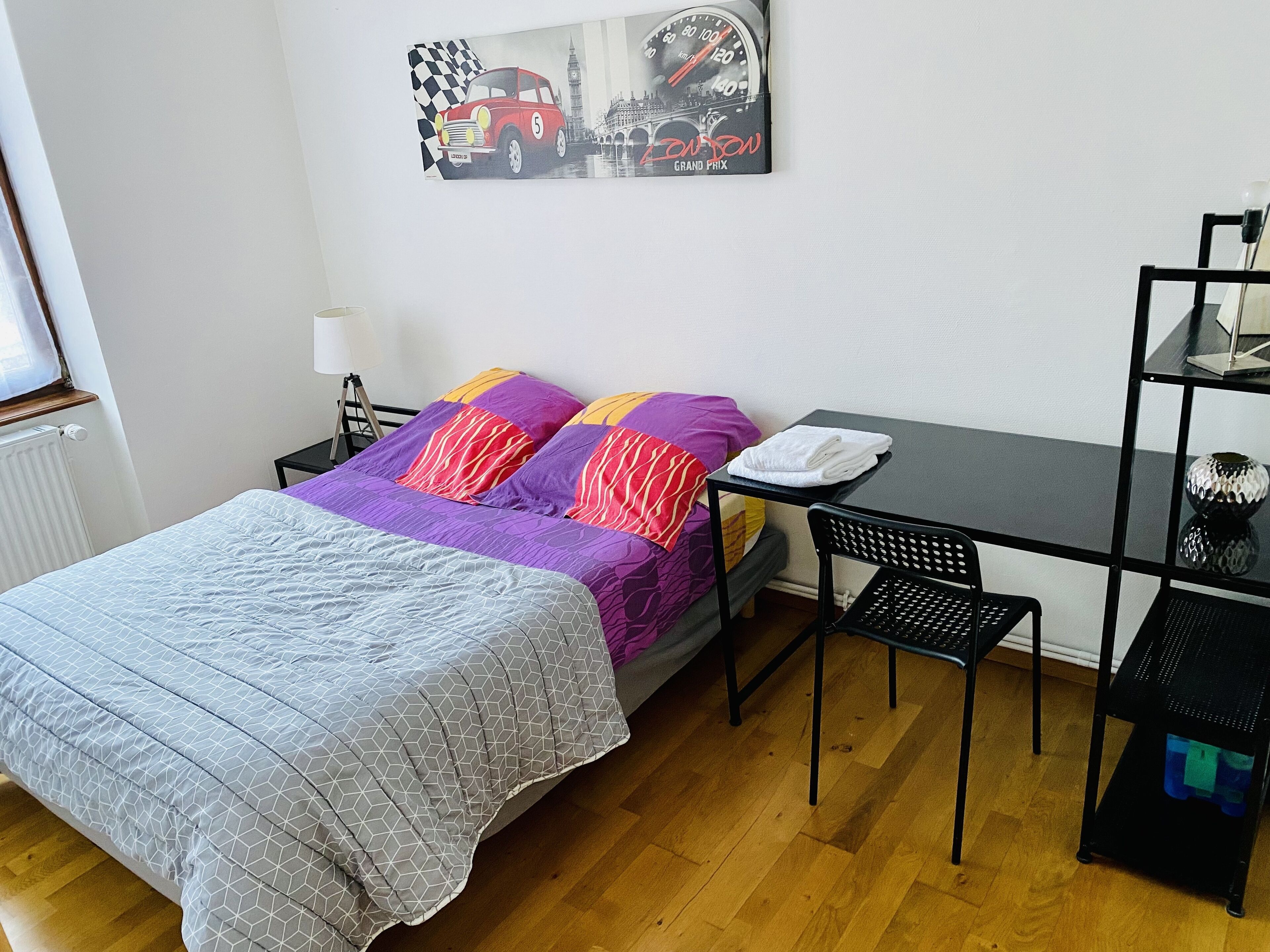 Ein Schlafzimmer mit einem Bett, einem Schreibtisch, einem Stuhl und einer Heizung.