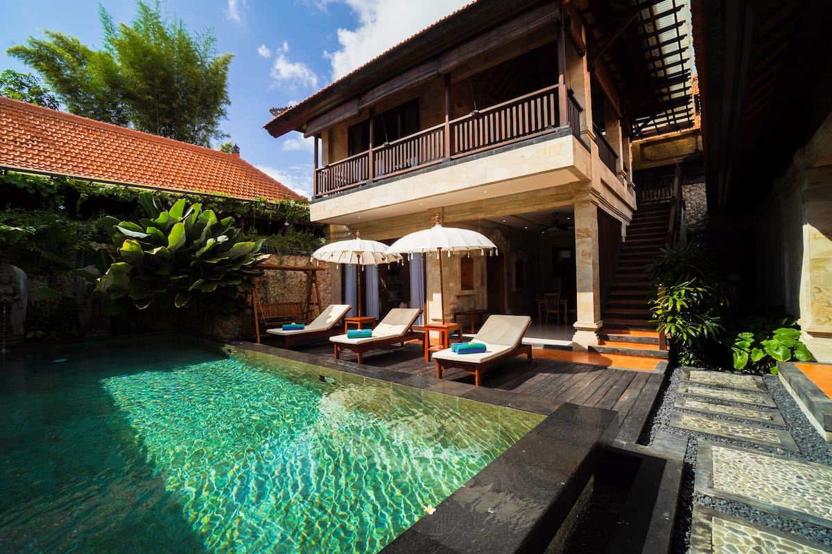 A poolside area with a clear pool, lounge chairs, and umbrellas.