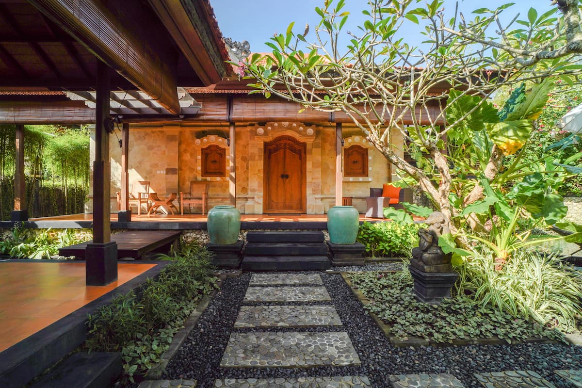 A traditional building with a wooden door, stone walls, and a garden with plants and a stone pathway.