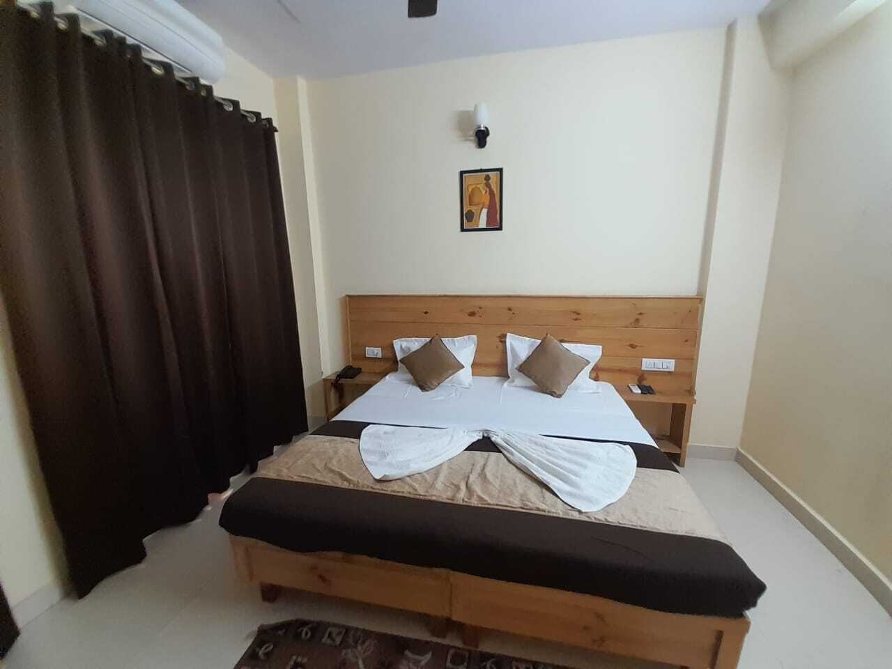 Un lit bien fait, avec une tête de lit en bois, une table de chevet et une lampe fixée au mur.