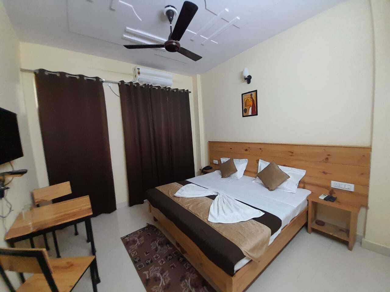 Una habitación de hotel con cama, escritorio, silla, ventilador de techo y televisor.