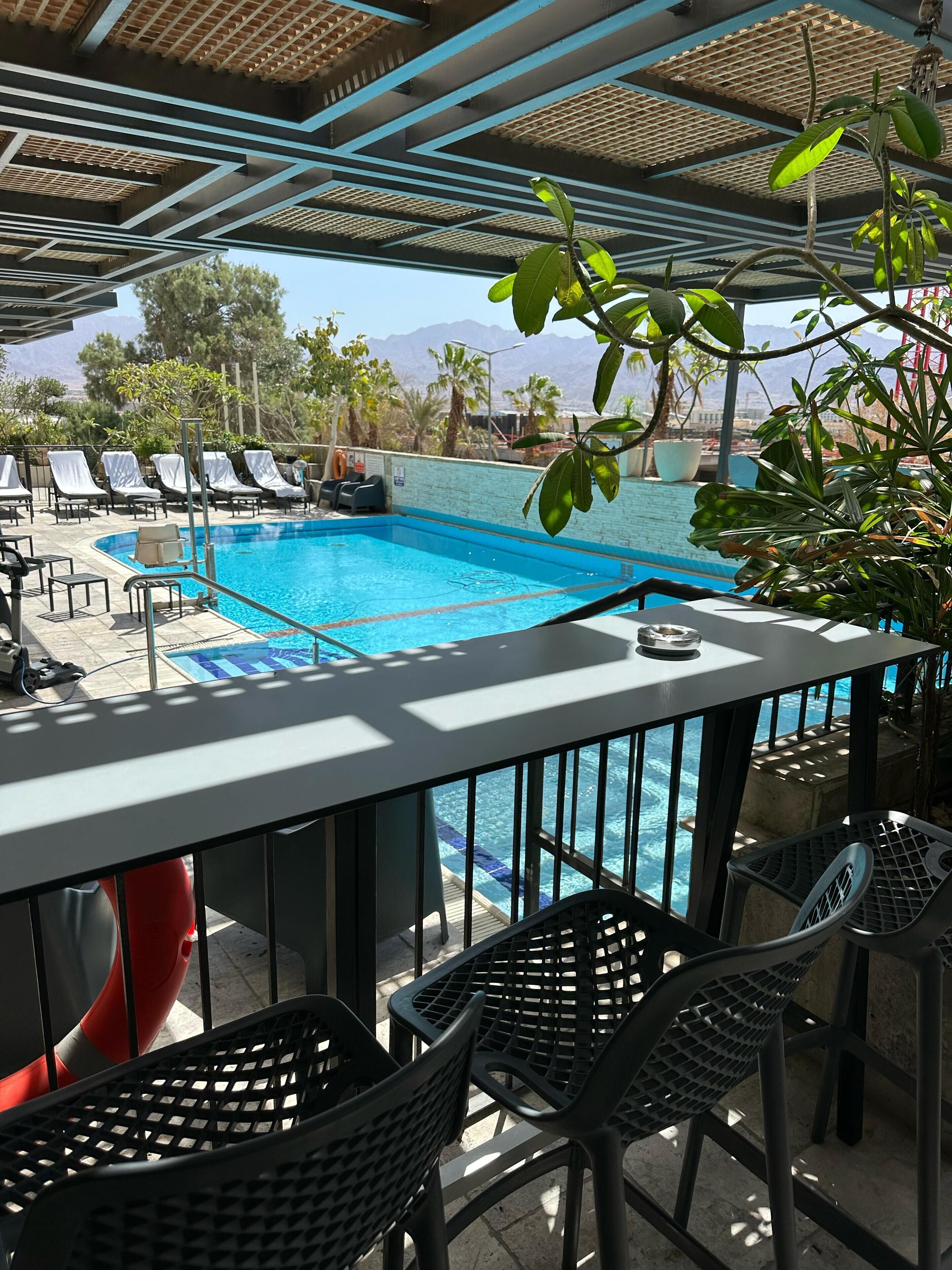 Un espace aménagé au bord de la piscine, avec des chaises longues, une piscine et une vue sur les montagnes.