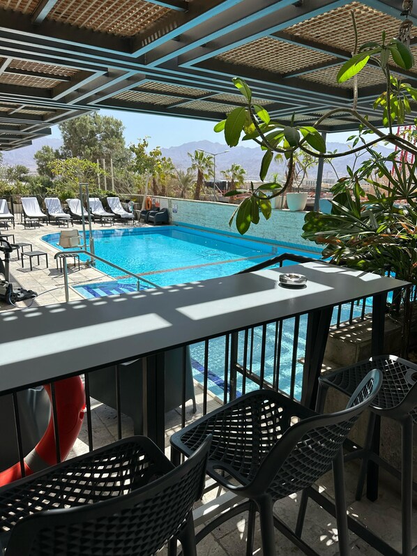 A poolside area with lounge chairs, a pool, and a view of mountains. - Comfort Hotel and Spa - Adults Only (Eilat)