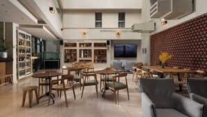 Um espaço amplo e interno com vários assentos, uma televisão e diversos objetos decorativos.