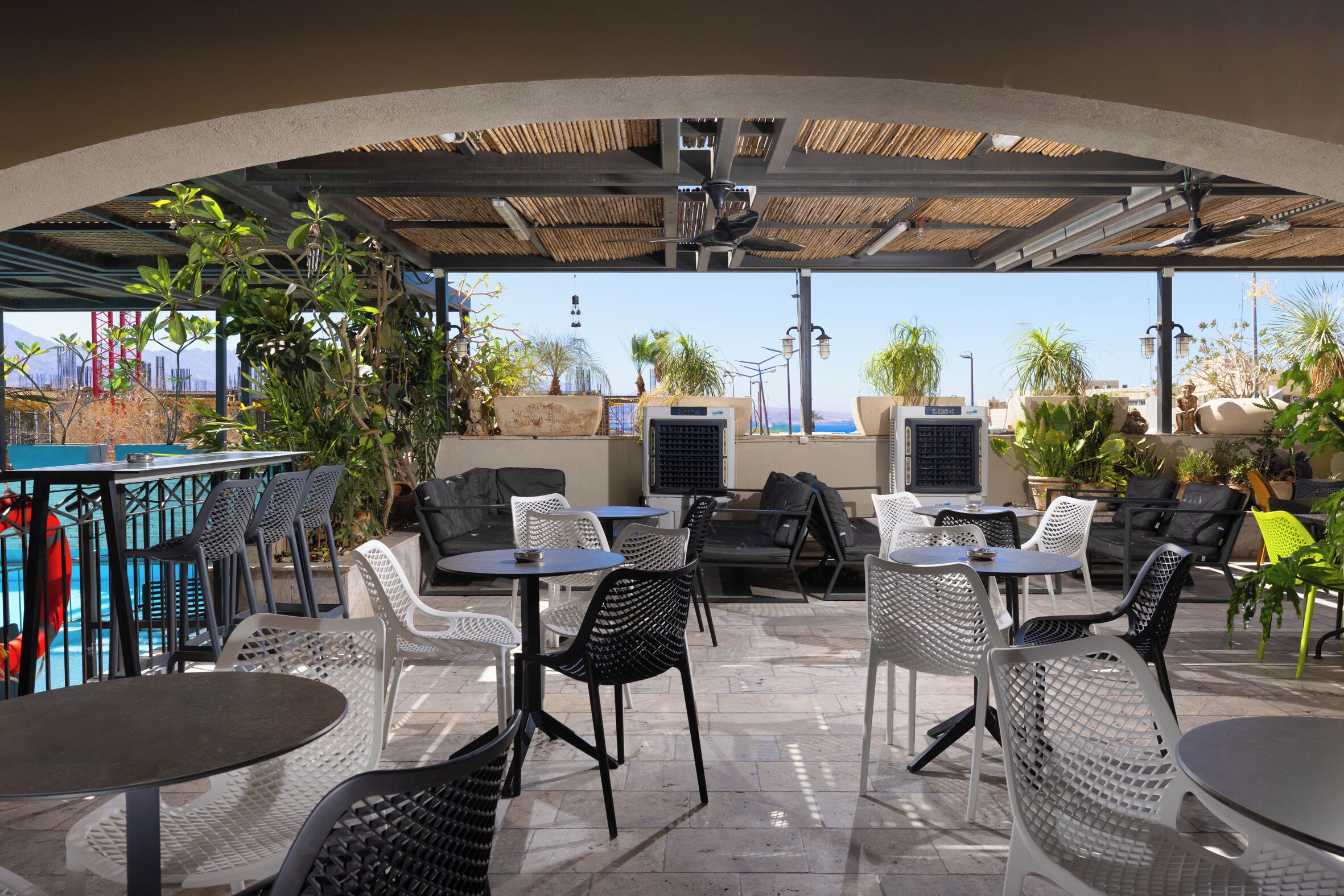 An outdoor patio with tables and chairs, air conditioning units, and potted plants.