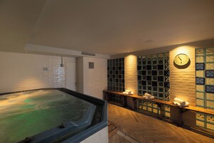 Un espacio de spa con un jacuzzi, bancos de madera y un reloj en la pared.