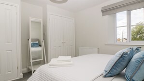 Quarto com cama grande, paredes brancas e janela.