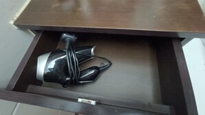 A drawer with a black and silver object inside, possibly a vacuum cleaner. - National Inn HK (Kowloon)