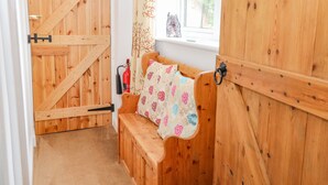 A wooden room with a bench, a window, and a door. - Willow Cottage (Norwich)