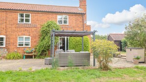 A brick house with a patio area, outdoor seating, and a garden. - Willow Cottage (Norwich)