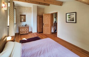 Cozy retreat with a large bed, dresser, and mirror, plus a door leading to another room.