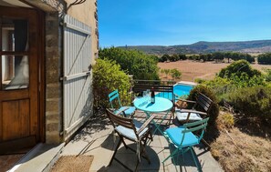 Relax in style with a round table and comfortable seating for six, surrounded by lush greenery and a serene natural backdrop.