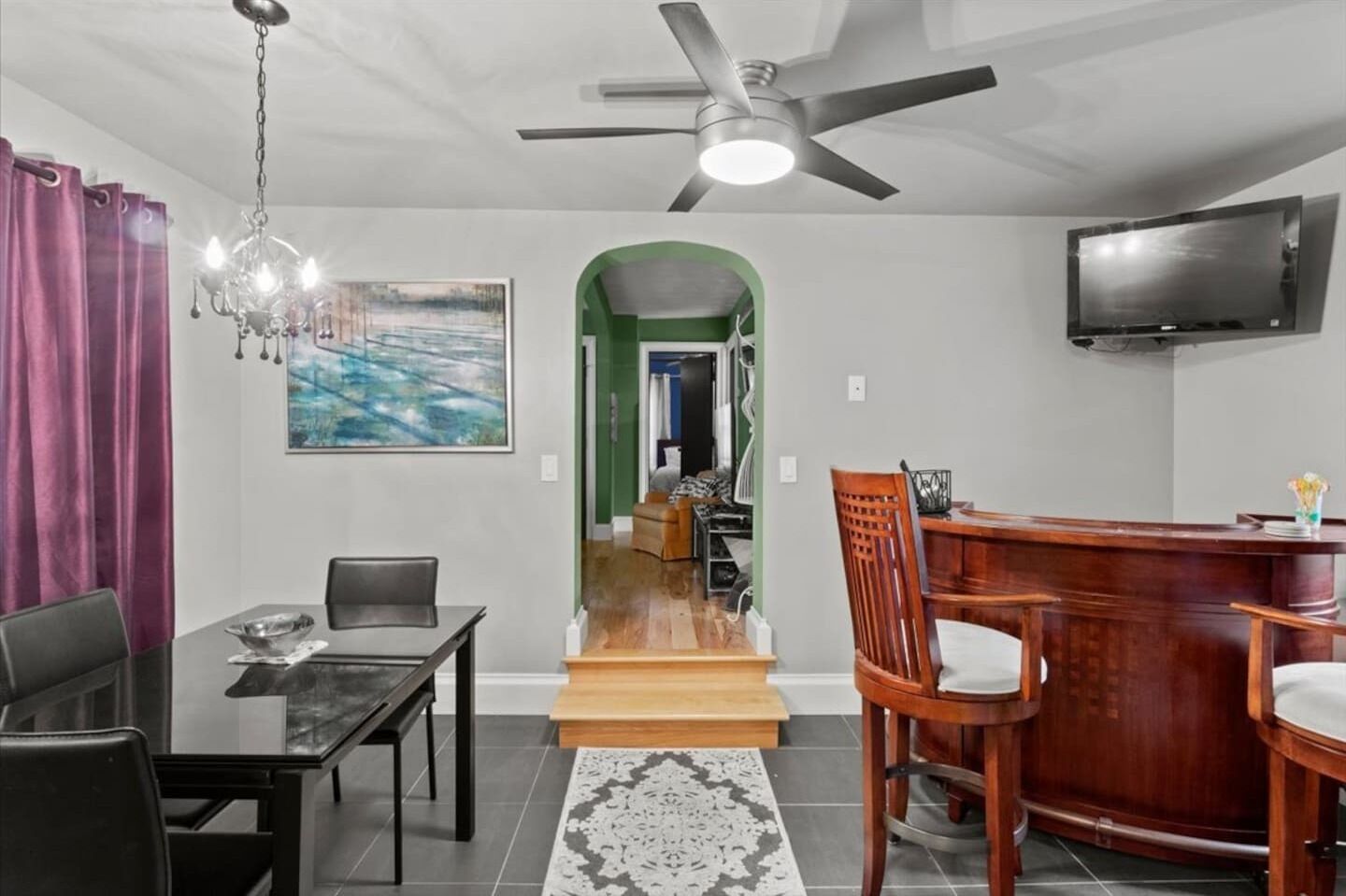 Un salon moderne comprenant un coin repas, un téléviseur fixé au mur et un escalier menant à une autre pièce.