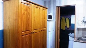 A wooden wardrobe, a white washing machine, and a bathroom with a sink and a mirror. - COLIVING 87 STUDIO NUMBER 1 (L'Hospitalet de Llobregat)