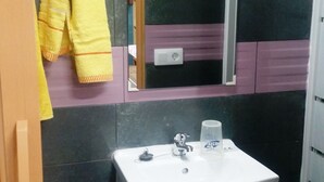 A bathroom with a white sink, a mirror, and a towel rack with a yellow towel. - COLIVING 87 STUDIO NUMBER 1 (L'Hospitalet de Llobregat)