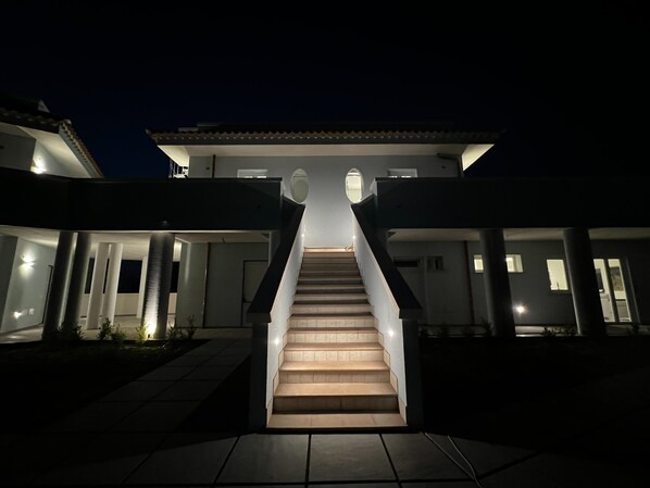 A modern building with a central staircase leading to a second-floor balcony.