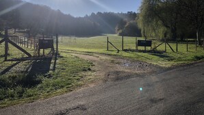 Paisaje rural con cielo despejado, un campo cercado y un letrero que dice 'LC Gites'.