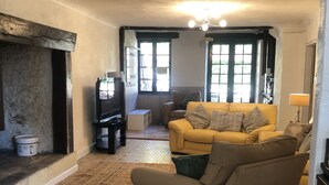 Una sala de estar acogedora con chimenea, un sofá amarillo y un televisor.