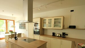 Een moderne keuken met een centraal eiland, een ingebouwde oven en een koffiehoek.