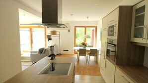 Een moderne keuken met een centraal eiland, houten kastjes en een eethoek met een tafel en stoelen.