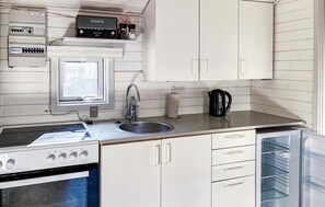 Une cuisine avec des armoires blanches, un évier en acier inoxydable, une cuisinière et un réfrigérateur.