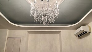 A modern living room with a large chandelier, a flat-screen TV, and an air conditioning unit mounted on the wall. - AZ Hotel Minamiawaji (Minamiawaji)