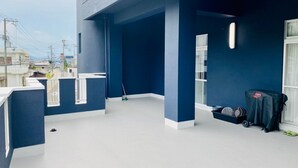 A spacious balcony with a blue exterior wall, a white floor, and a view of the cityscape. - AZ Hotel Minamiawaji (Minamiawaji)
