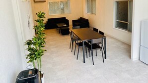 A modern dining area with a wooden table and chairs, a black sofa, and a potted plant. - AZ Hotel Minamiawaji (Minamiawaji)