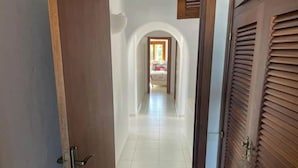 Ein Flur mit Fliesenboden, der zu einem Zimmer mit Bett und Fenster führt.