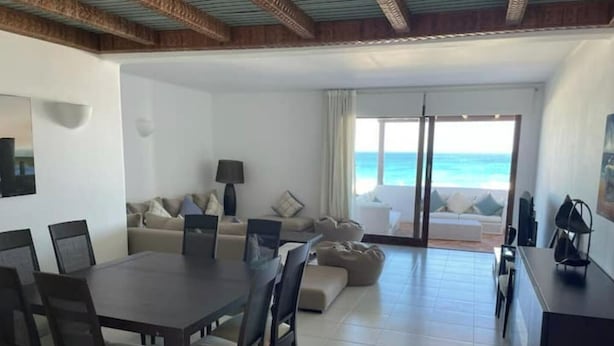 Ein geräumiger Wohnbereich mit Esstisch, Sofas und Meerblick.