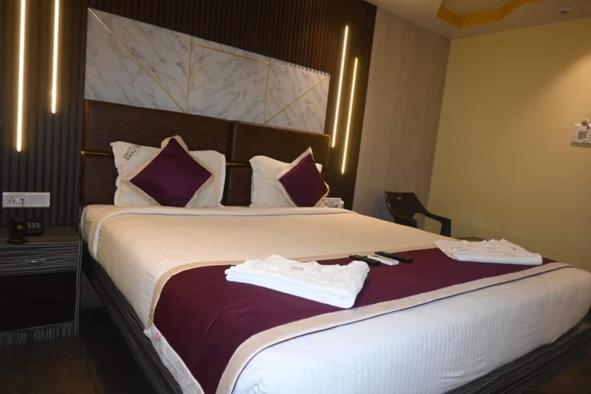 A hotel room with a large bed, a marble headboard, and a nightstand with a phone and a lamp.