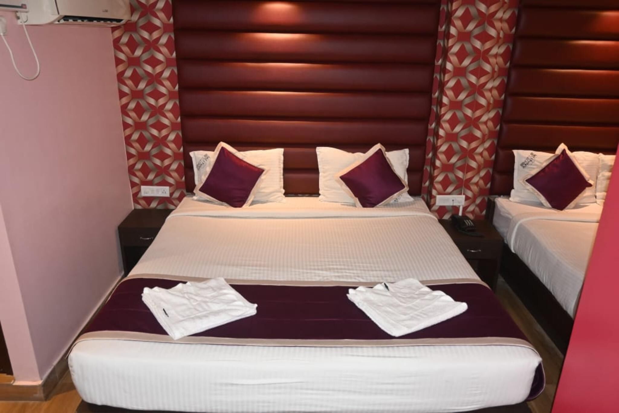 A hotel room with a large bed, two bedside tables, and a headboard with a geometric pattern.