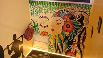 A staircase with a mural featuring a woman and a man lifting weights, a window above, and a ceiling light fixture.